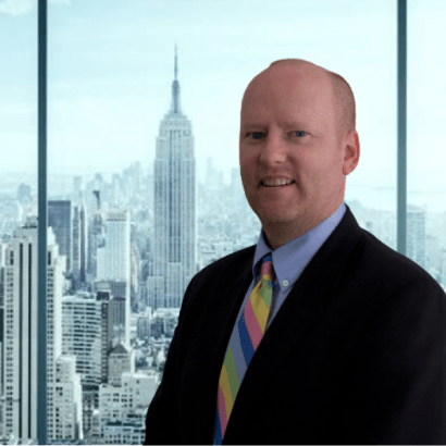 Kevin Owens, President and CEO, standing in front of window with city skyline in background