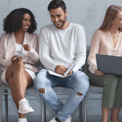 Talent Community image: Happy people are seated, holding phones, laptops, and tablets.