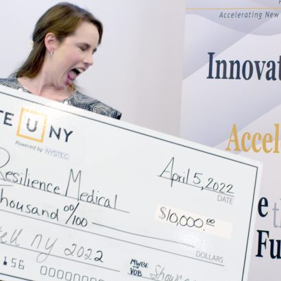 Startup accelerator image: A happy woman holds a customized large prizewinning check.